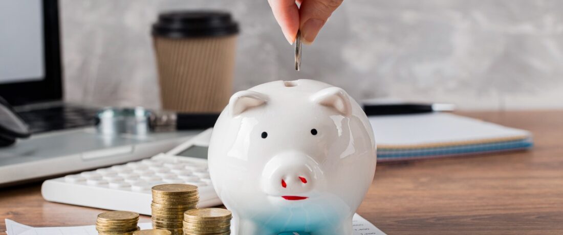 Mano de una persona insertando una moneda en una alcancía